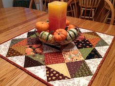 a table topped with a bowl of fruit and a candle on top of a wooden table