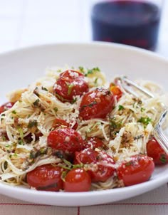 a white bowl filled with pasta and cherry tomatoes