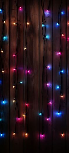 colorful lights are hanging on the wooden wall in front of it's dark background