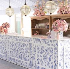 a blue and white bar with flowers on the counter top, hanging from ceiling lights