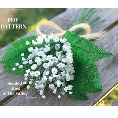 a bunch of white flowers sitting on top of a wooden table next to green leaves