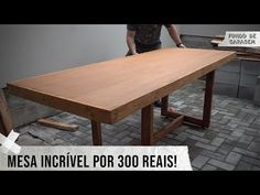 a man standing next to a wooden table on top of a brick floor with the words mesa incrivel por 300 reais