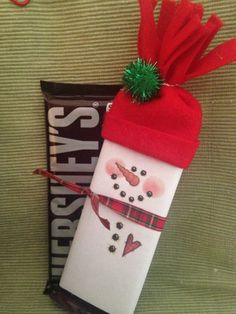 a candy bar wrapped in red and white paper with a snowman hat on top