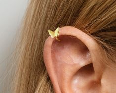 a close up of a person's ear with a small yellow butterfly on it