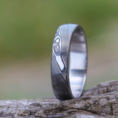 a wedding band with an engraved design on it sitting on top of a piece of wood