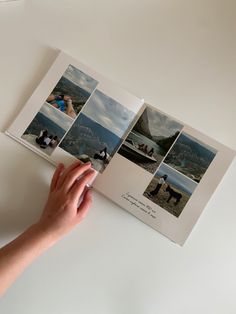 a hand holding an open photo book with pictures on the cover and in front of it