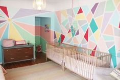 a baby's room decorated in pastel colors with geometric wallpaper and crib