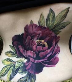 a woman's back with a flower tattoo on her lower body and the bottom part of her stomach