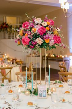 a centerpiece with flowers and candles on a table in a banquet hall or wedding reception