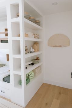 a bedroom with white shelving and wooden floors