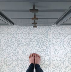 a person standing in front of a tiled wall with their feet up on the floor