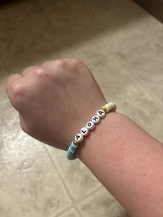 a child's arm with a bracelet that says love on it and two beads attached to the wrist