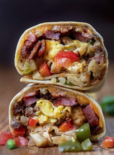 two breakfast burritos stacked on top of each other with bacon, eggs and peppers