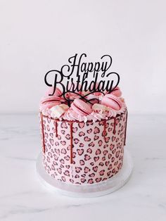 a birthday cake with pink frosting and leopard print icing, on a marble surface