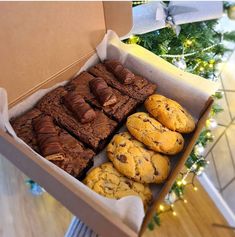 a box filled with cookies and brownies next to a christmas tree