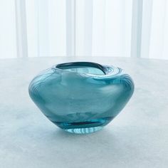 a blue glass vase sitting on top of a white tableclothed floor next to a window