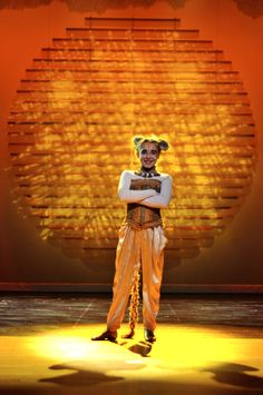 a man in costume standing on stage with his arms crossed