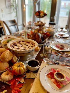 a table set for thanksgiving dinner with pies and other foods