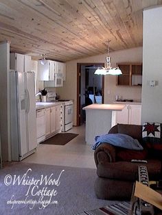 a kitchen and living room are shown in this image, with wood paneling on the ceiling