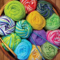 colorful balls of yarn in a basket with knitting needles