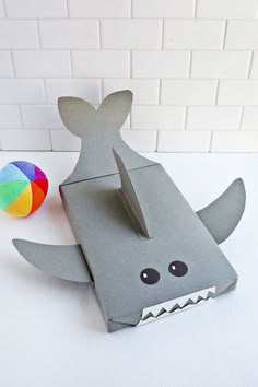 an origami shark with a ball on the ground next to it's mouth