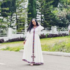 a woman in a white dress is standing on the street with her arms behind her head