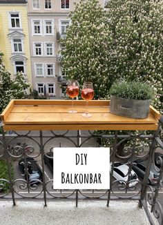 two glasses of wine sitting on top of a table with a sign that says diy balkonbar