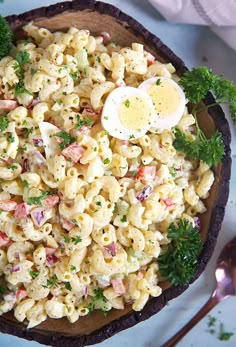 a wooden bowl filled with macaroni salad and an egg on the top of it