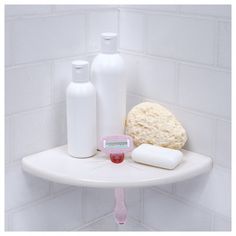 a bathroom shelf with soap, toothbrushes and other items on it in front of a white tiled wall