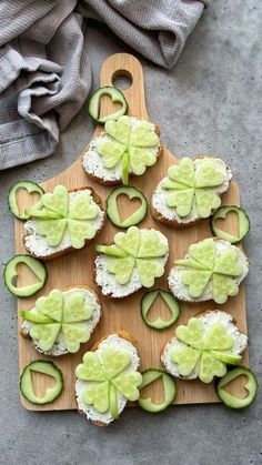 cucumber and cheese appetizers are arranged on a cutting board with a cloth in the background