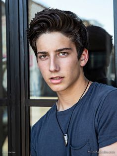 a young man is standing in front of a glass door and looking at the camera