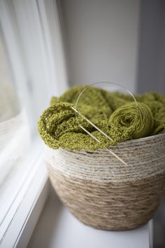 green yarn in a basket sitting on a window sill