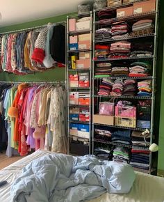 the closet is full of clothes and other items for sale on shelves in front of a bed