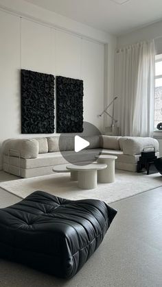 a living room filled with white furniture and black art work on the wall behind it