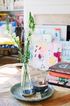 a glass vase filled with flowers sitting on top of a wooden table next to books