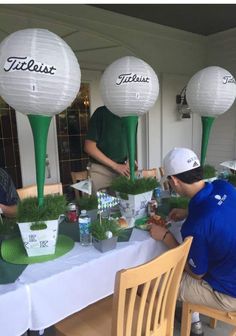 several people sitting at a table with plants and paper lanterns in the shape of golf balls