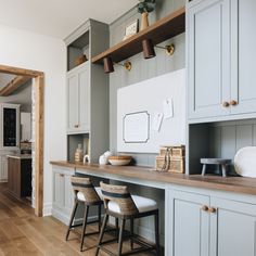 a kitchen with wooden flooring and gray painted cabinets, counter tops and stools