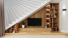 an entertainment center with bookshelves and a television on the wall, under a stair case