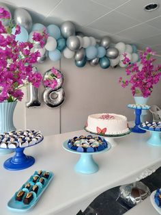 a table topped with cakes and cupcakes next to balloons