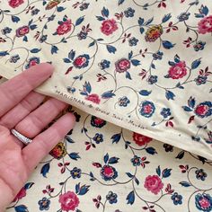 a woman's hand is holding onto a white and blue flowered dress with pink flowers on it