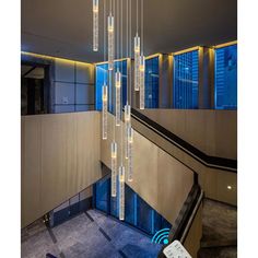 a modern chandelier hanging from the ceiling in a lobby with stairs and windows