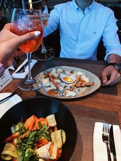 a man sitting at a table in front of a plate of food and wine glasses