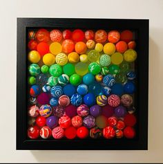 an art piece with many different colored balls in the center and black frame on the wall