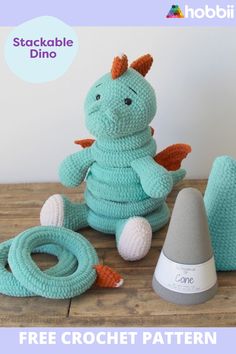 a crocheted dragon sitting next to two other items on top of a wooden table