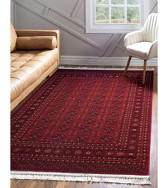 a living room area with a couch, chair and rug on the floor in front of a window