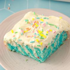 a piece of cake with white frosting and sprinkles on a plate