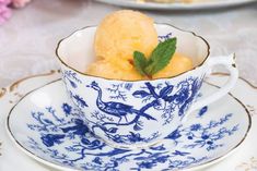 a blue and white tea cup filled with ice cream on top of a saucer