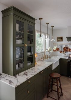 a kitchen with green cabinets and marble counter tops