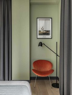 an orange chair sitting next to a bed in a room with green walls and wooden floors