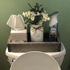 a white toilet sitting in a bathroom next to a wooden box filled with bottles and flowers